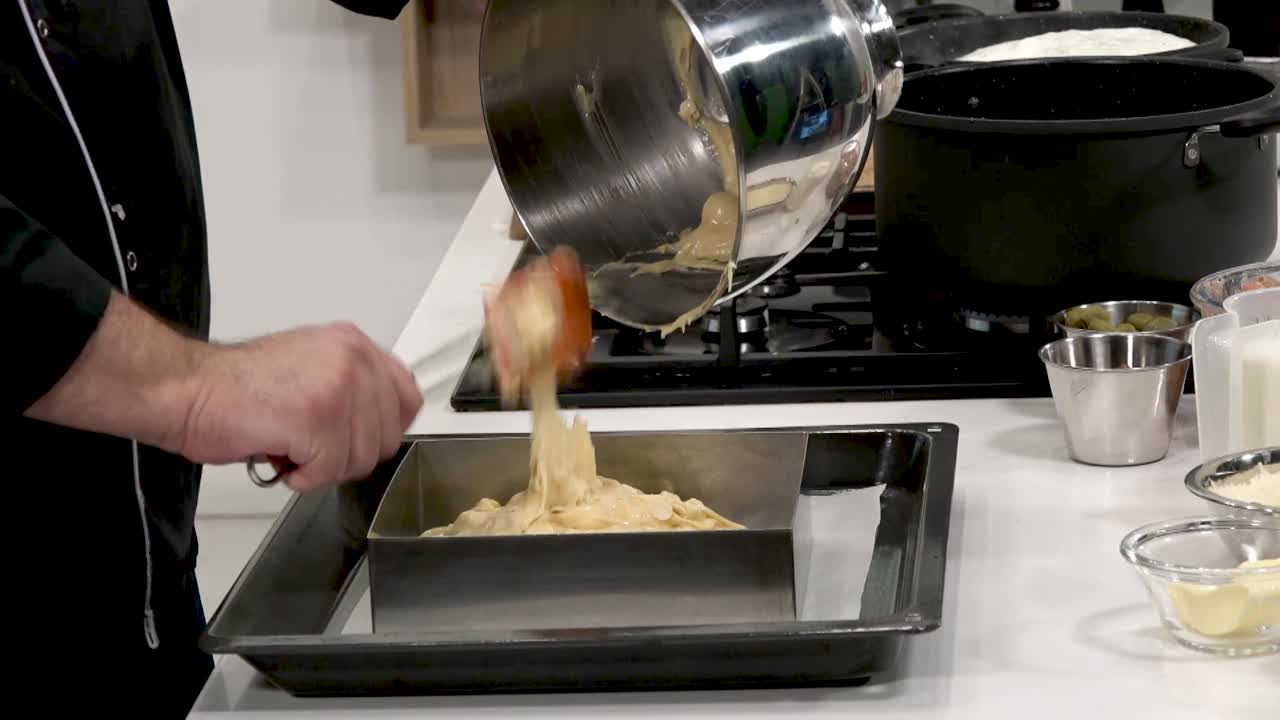 Chef demonstrates precise cake batter preparation in a contemporary kitchen. Ingredients are mixed methodically, showcasing essential techniques for bakers