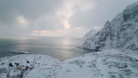 aerial view of remote fishing village at the bottom of lofoten islands snowy mountain and idyllic blue ocean