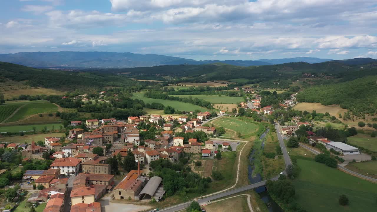 Drone view of a beautiful Tuscan landscape with village, hills, river and clouds on a sunny day.