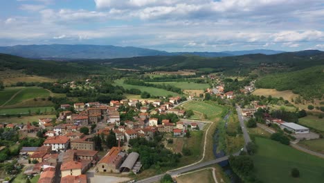 drone view of a beautiful tuscan landscape with village, hills, river and clouds on a sunny day.