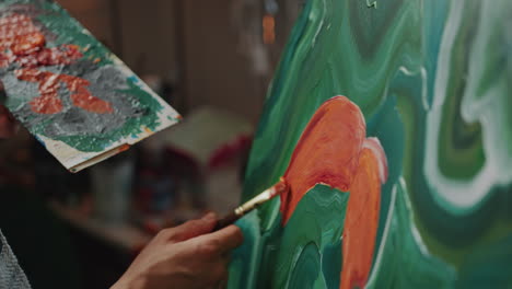 close-up of artist holding palette of mixed colors and painting on canvas