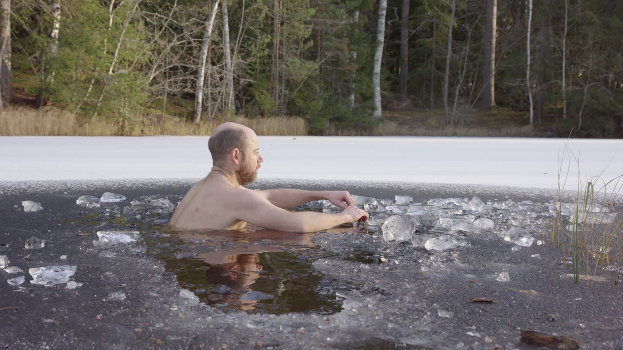 슬로우 모션 - 남성 얼음 목욕하는 사람이 시작하기 위해 얼음물에 앉습니다.