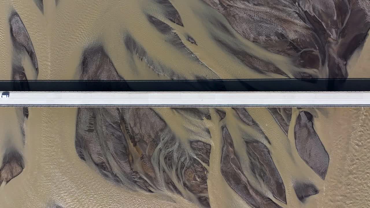 Cars on bridge over glacial river in Iceland. Aerial top down shot. Sunny day on Icelandic island. Travel scene