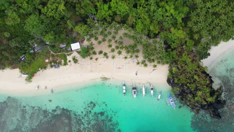 Vista-De-Arriba-Hacia-Abajo-De-Drones-Sobre-Canoas-Bangka-Estabilizadoras-En-La-Playa-Arenosa-De-El-Nido