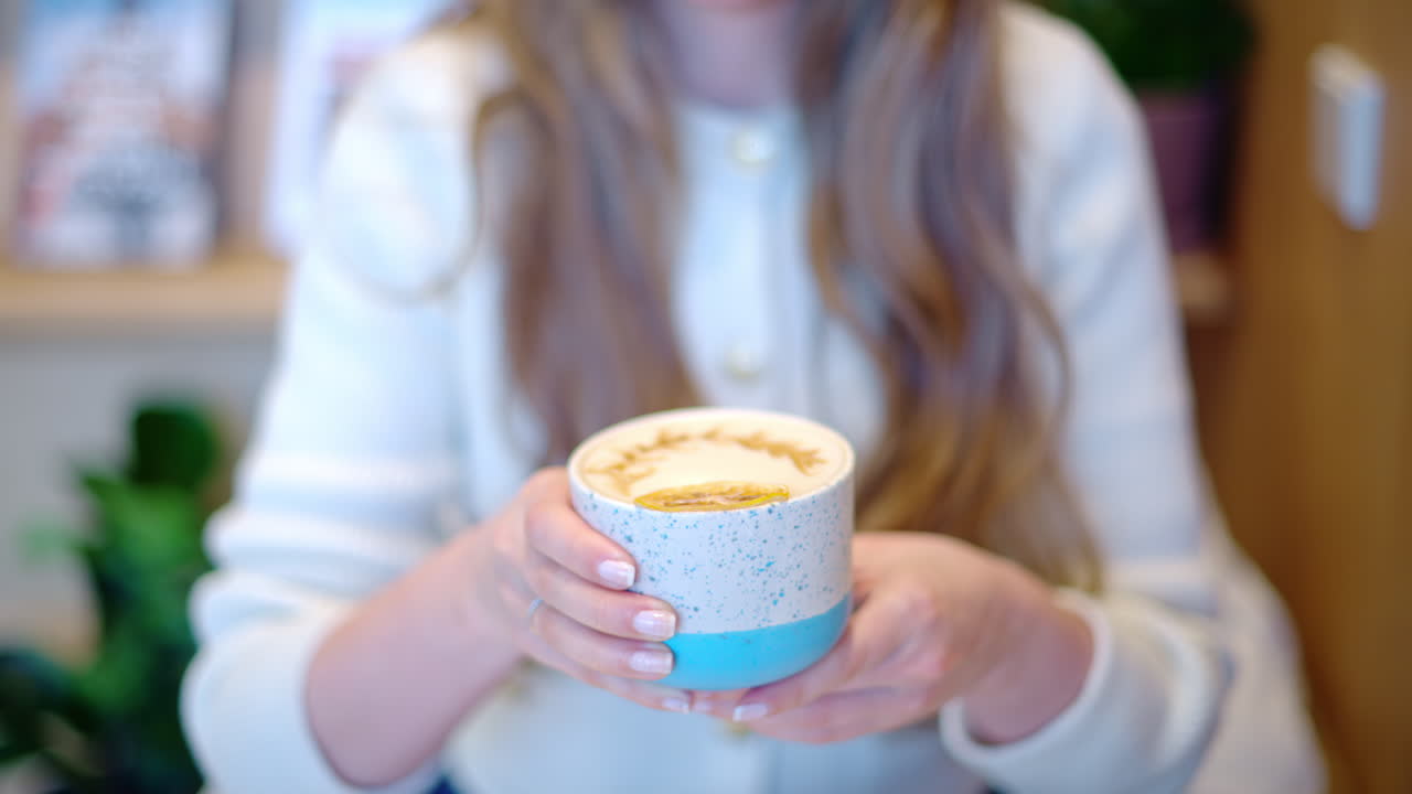 Woman drinking latte art coffee from ceramic cup in a cafe