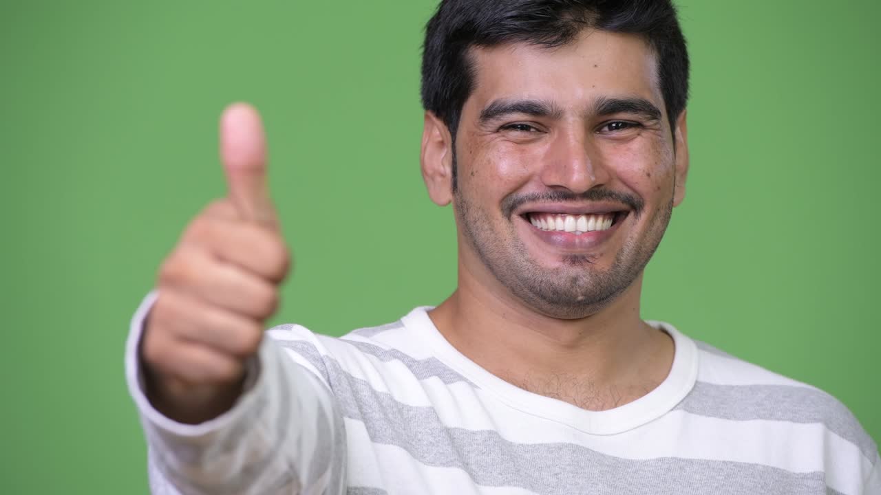 Young handsome Persian man giving thumbs up