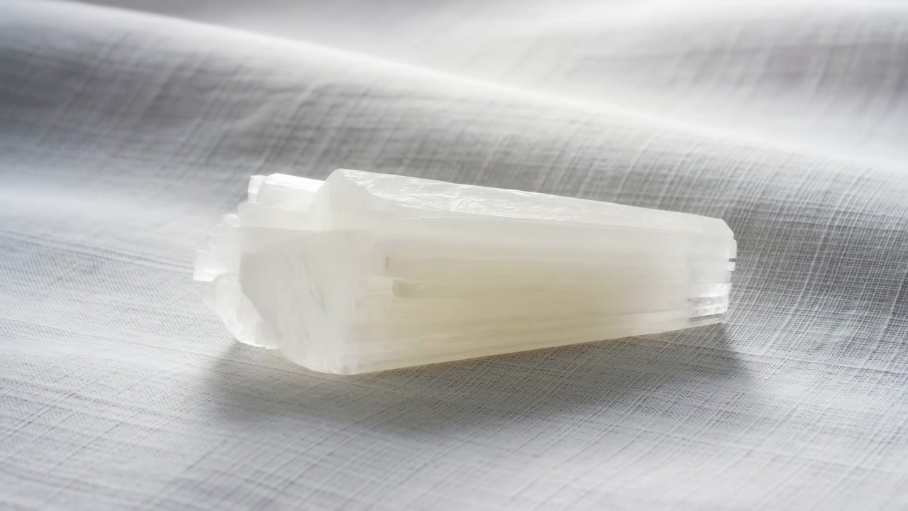 白い素材の断片。目に見える動きや変化はなく、おそらく布地か紙のような質感のある表面に置かれている。白とグレーのアクセント。