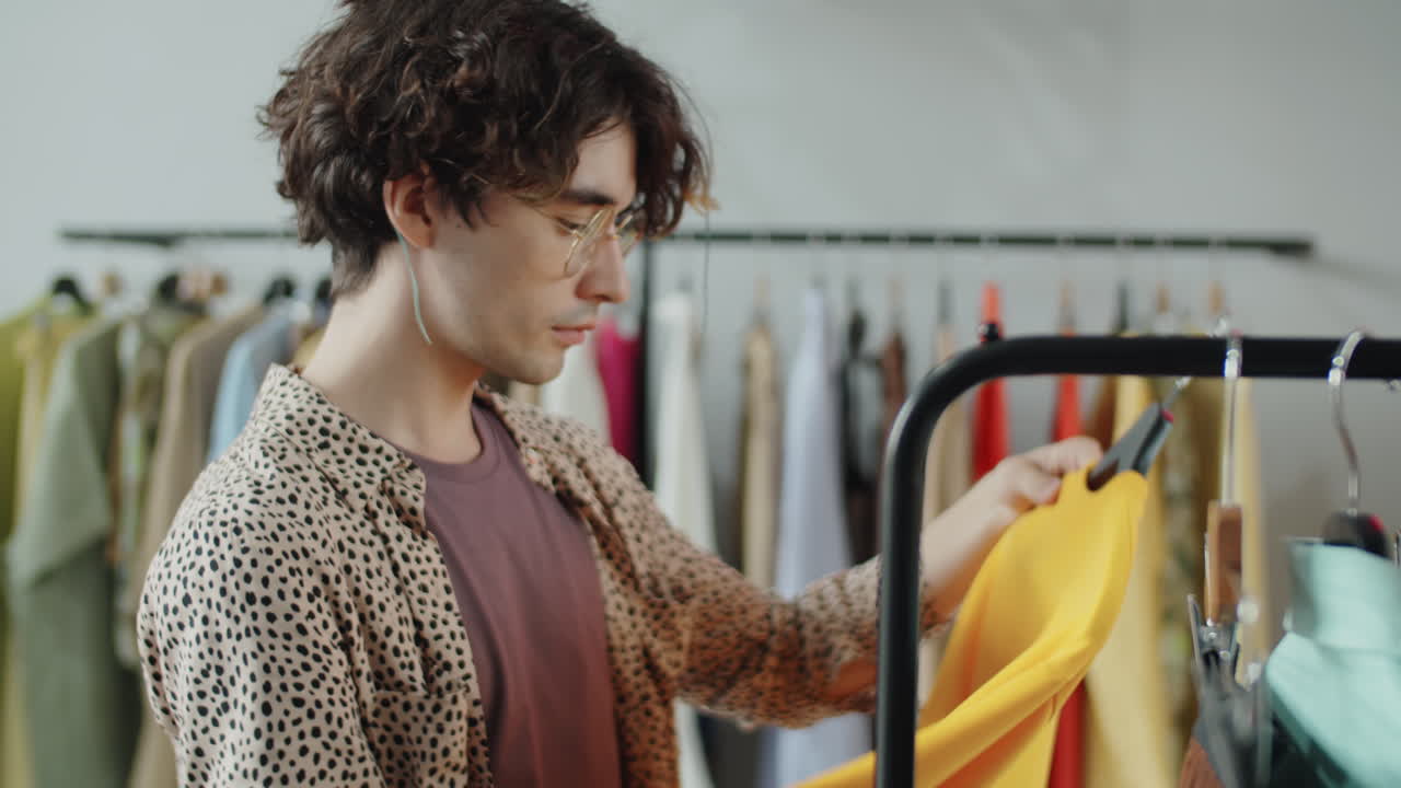Giovane uomo che sceglie un capo d'abbigliamento in un negozio di abbigliamento.