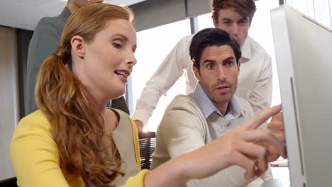 businessman and coworkers discussing over computer at desk