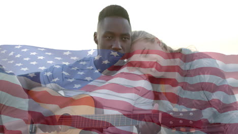 Animación-De-La-Bandera-De-Estados-Unidos-Sobre-Diversos-Amigos-Tocando-La-Guitarra-En-La-Playa.