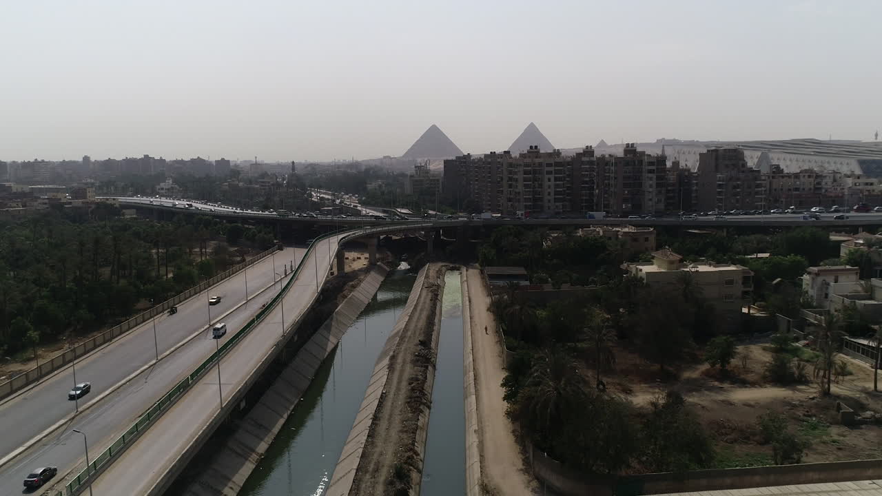 toma aérea de las pirámides de egipto en giza en el fondo de una rama del río nilo en el primer plano de la rama de maryotya