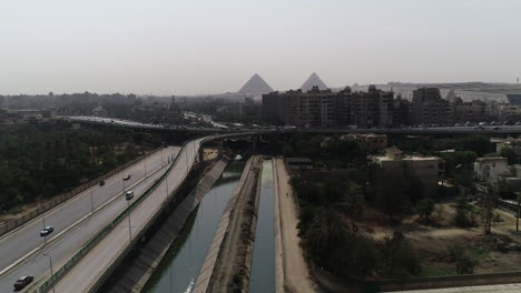 Aerial-Shot-for-The-Pyramids-of-Egypt-in-Giza-in-the-background-of-a-branch-from-the-River-Nile-in-the-foreground-Maryotya-branch