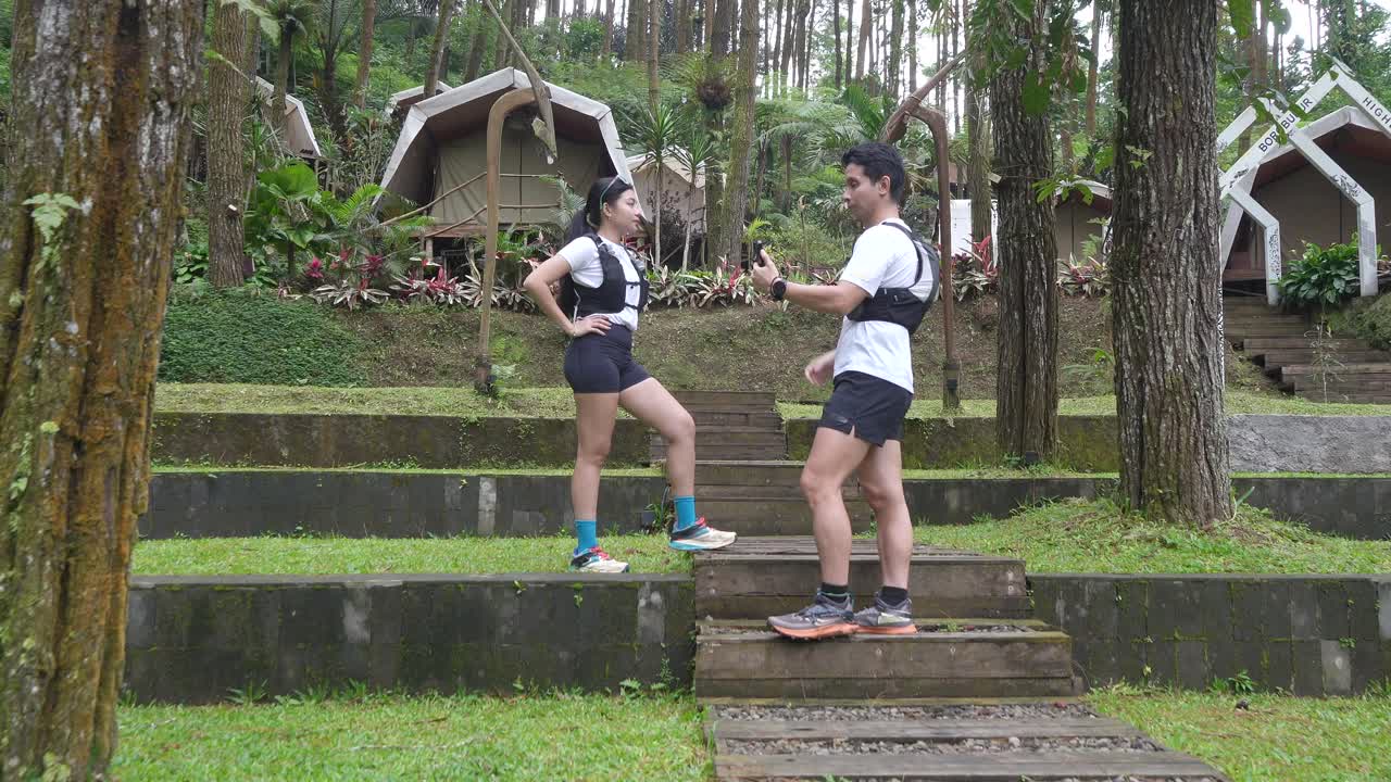 Asian couple resting and talking during outdoor workout in forest trail