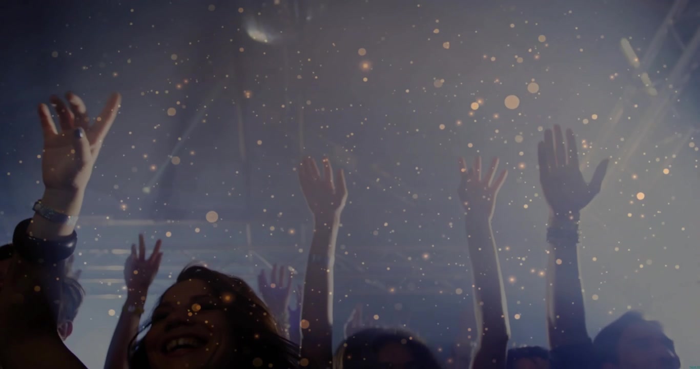 Partecipanti al concerto che alzano e agitano le mani in un club poco illuminato, reagendo al beat drop, con coriandoli che fluttuano.