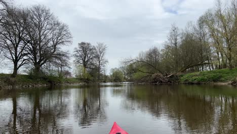 FPV-POV-Montando-Y-Remando-En-Un-Kayak-A-Lo-Largo-De-Un-Río-Con-árboles-Al-Lado