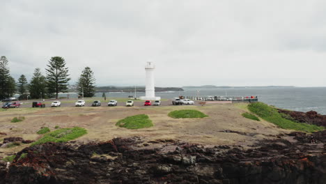 Aerial-drone-shot-pulling-away-from-Kiama-lighthouse-to-reveal-more-of-the-cliffs-and-headland-on-a-stormy-day,-South-coast-NSW,-Australia