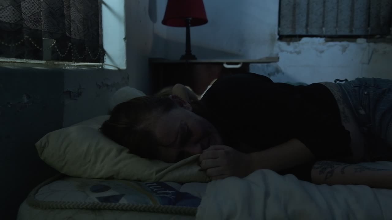 Dolly push in of woman crying in bed