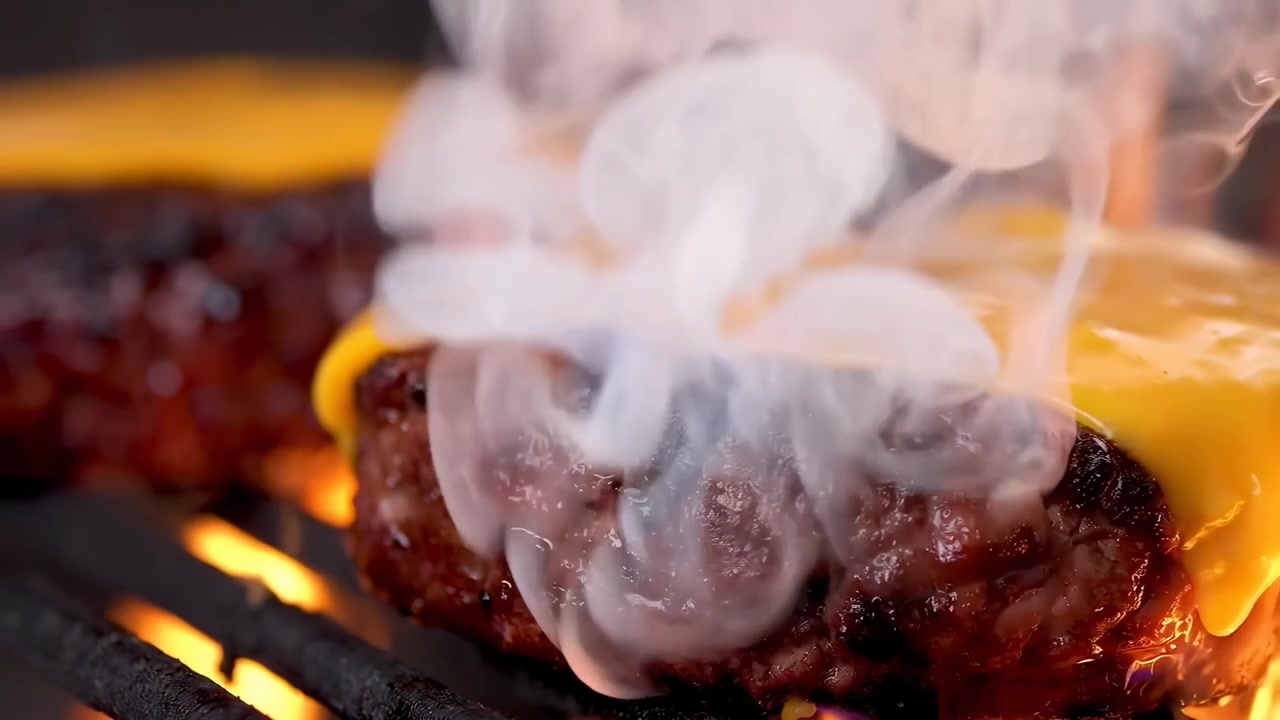 Cheeseburger succosi con formaggio fuso che sfrigolano su una griglia calda