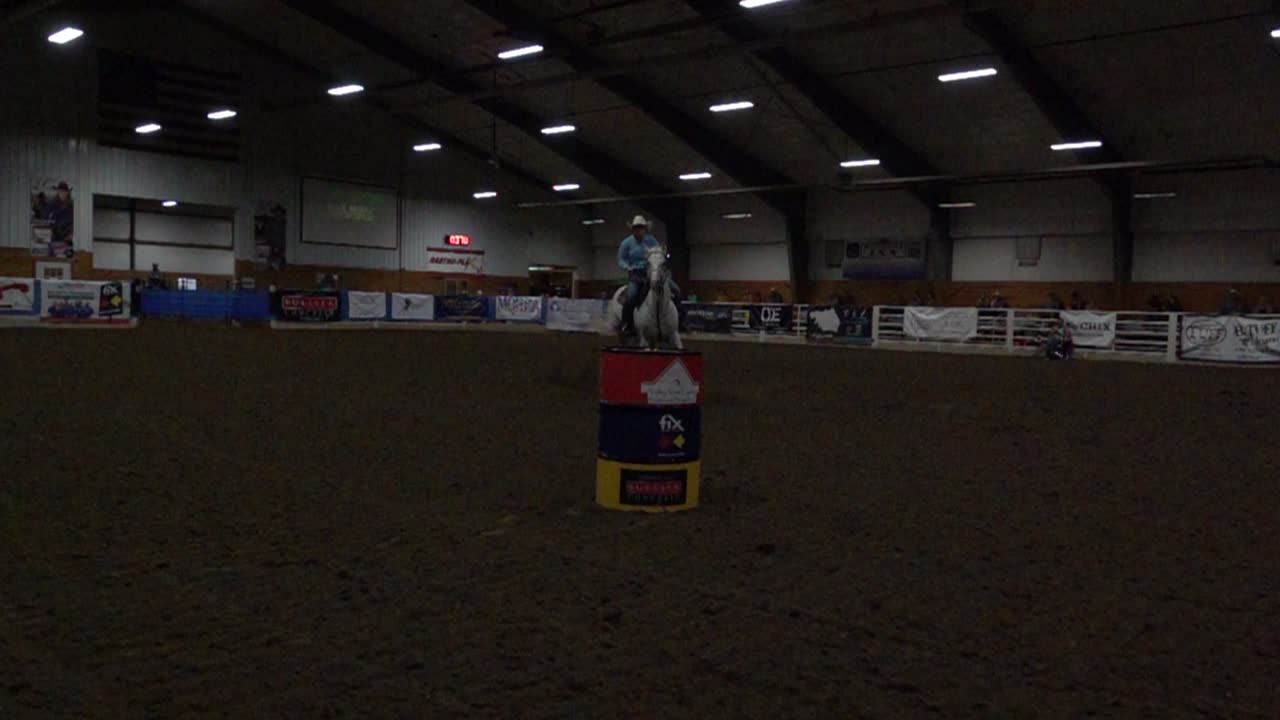 Cowgirl su cavallo bianco che fa barrel racing al rallentatore
