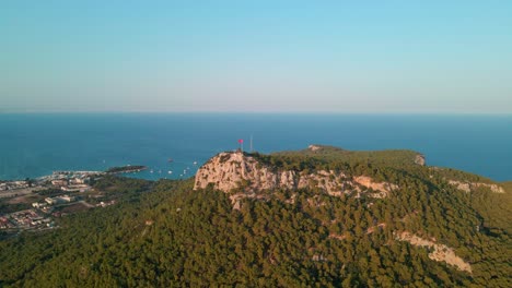 imágenes aéreas de drones 4k de una colina con la bandera de turquía ondeando sobre la ciudad de kemer