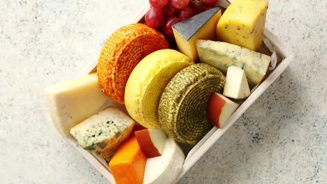 fresh and delicious different kinds of cheeses placed in wooden crate with grapes