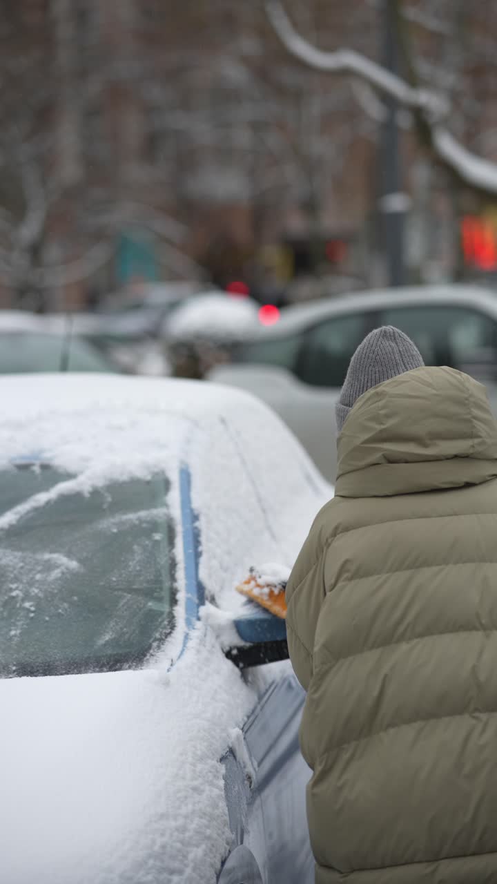 persona quitando la nieve de un coche en invierno