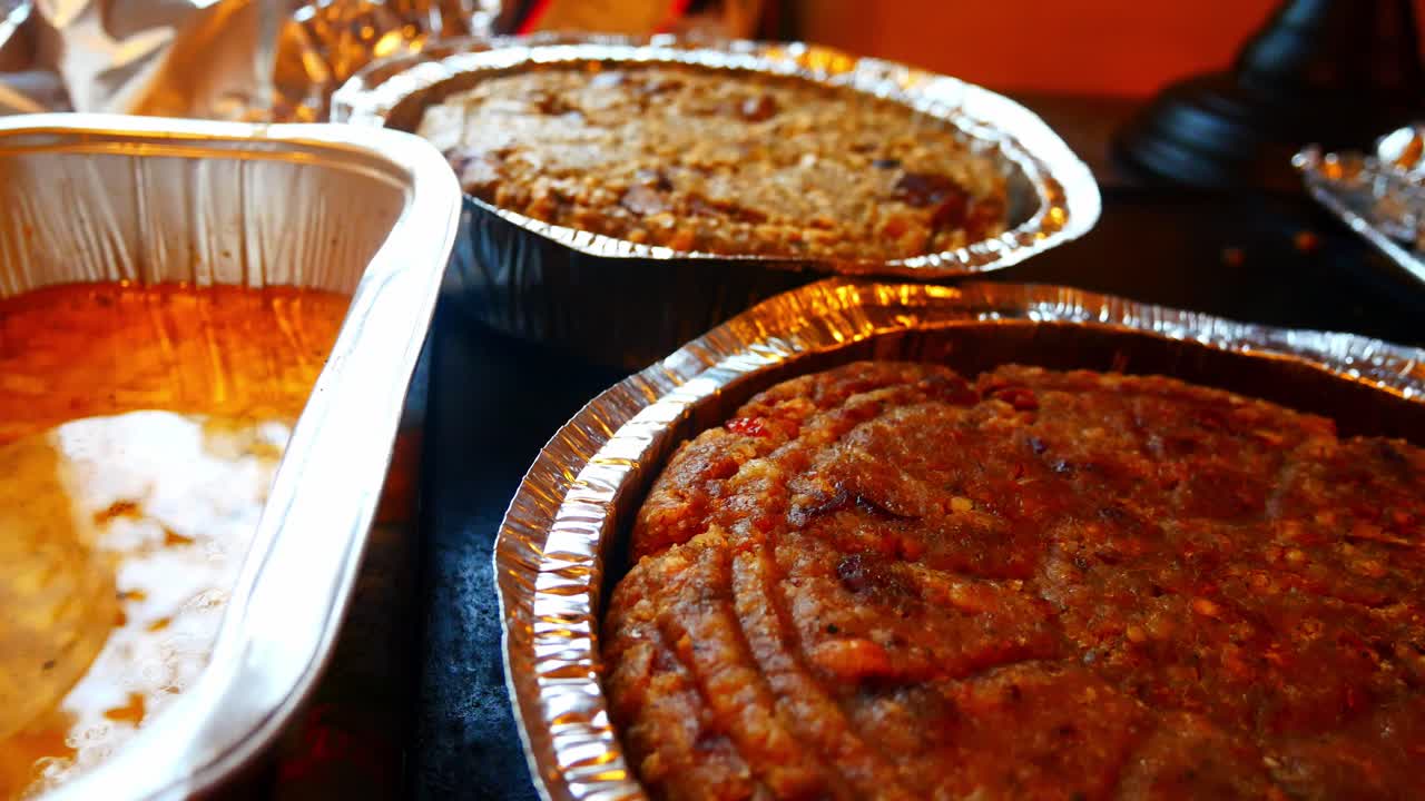 Selezione di ripieni per salsicce vegetariane e tradizionali di carne in vassoi di alluminio su un bancone da cucina, ripresa con dolly a destra