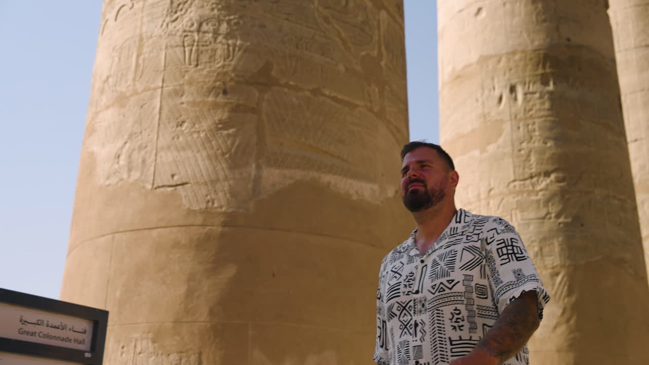 Man Walking Through Columns With Hieroglyphs At Luxor Temple In Egypt. pullback, tracking shot