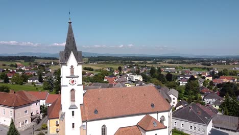 drone flies by a church in austria - blue sky and sunny weather - steinakirchen am forst