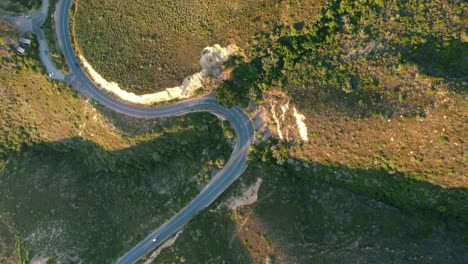 car driving on chapmans peak road on coast of cape town at sunset, top down aerial