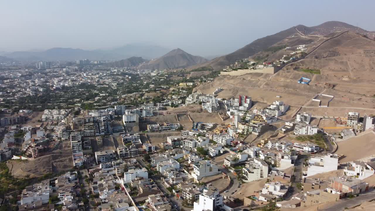शुष्क पहाड़ी ढलानों पर बने एक फैले हुए शहर का हवाई दृश्य