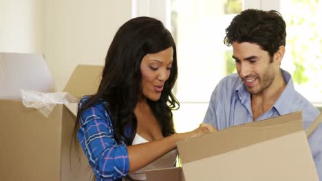 Young-couple-unpacking-carton-boxes-in-their-new-house