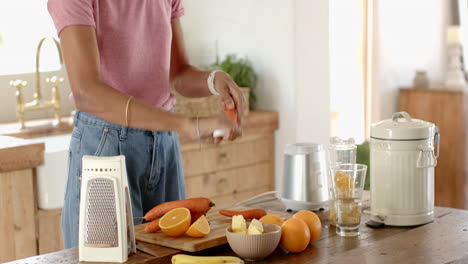 preparing fresh juice, woman slicing carrots and oranges in cozy kitchen, at home