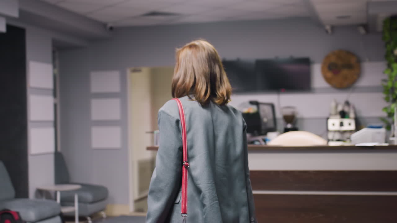 Businesswoman walking in office corridor, wearing formal attire with shoulder bag, modern professional environment, confident woman in workspace, corporate life