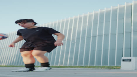 female soccer athlete juggling a ball on sidewalk