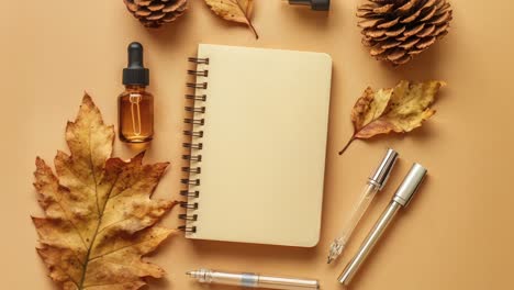 autumnal desk setup with notebook, pens, leaves, and essential oil