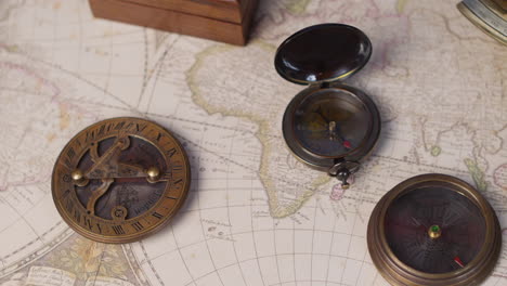 vintage compass, sundial, telescope and a nautical sextant lying on ancient world map