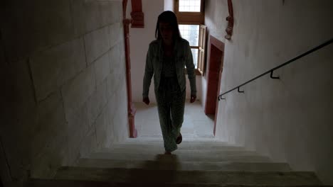 woman walking up the stairs in a dark hallway