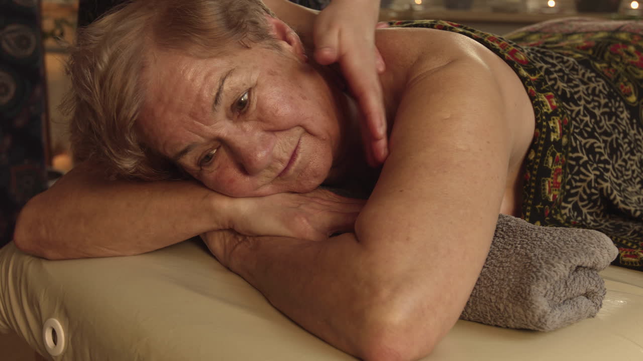 Close de uma senhora recebendo tratamento de massagem cervical em um spa
