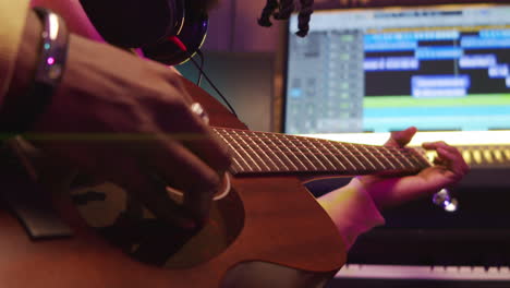 músico afroamericano tocando la guitarra en un estudio de grabación