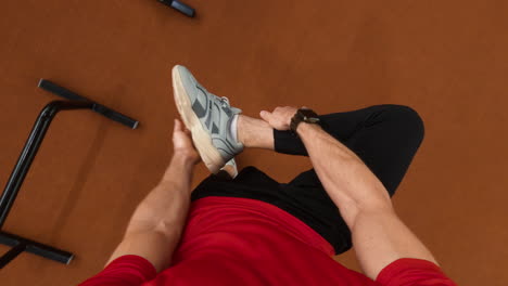 first-person view of a person in a red shirt holding their foot and sneaker