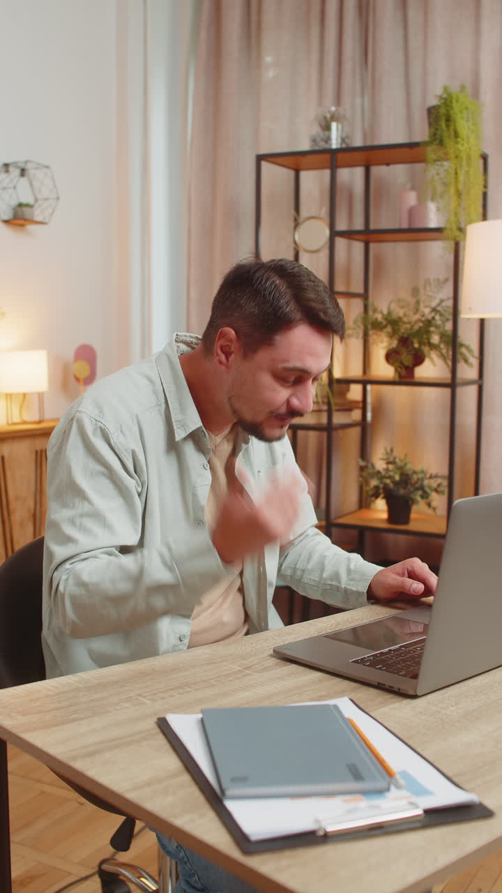 joven caucásico independiente que tiene una llamada de video a través de una computadora portátil sentado en la mesa de la oficina de casa