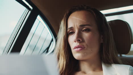 Portrait-of-focused-business-lady-looking-at-papers-with-data-in-business-car.