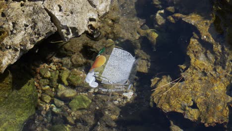 product label plastic floats in clean seawater between rocks