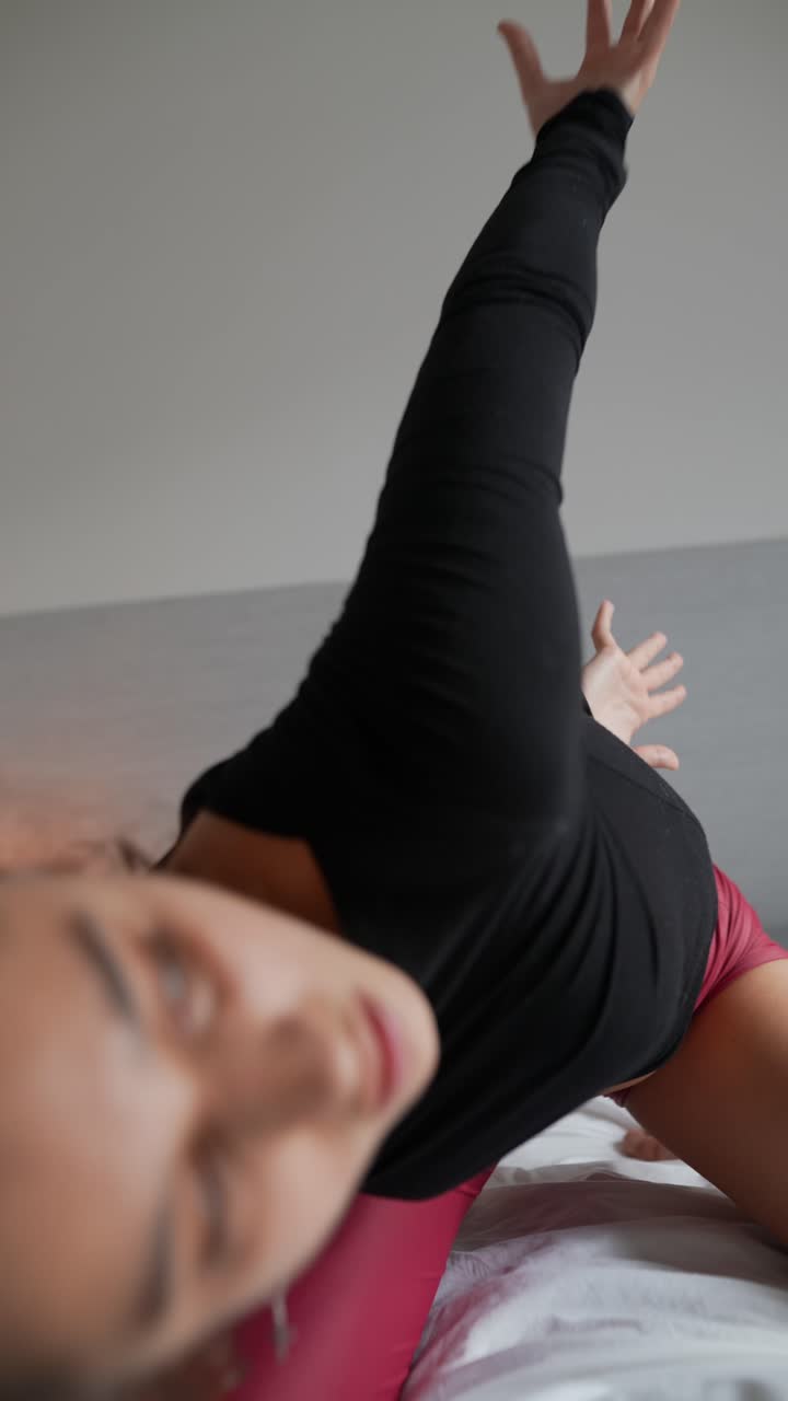 Woman practicing yoga or stretching on a bed