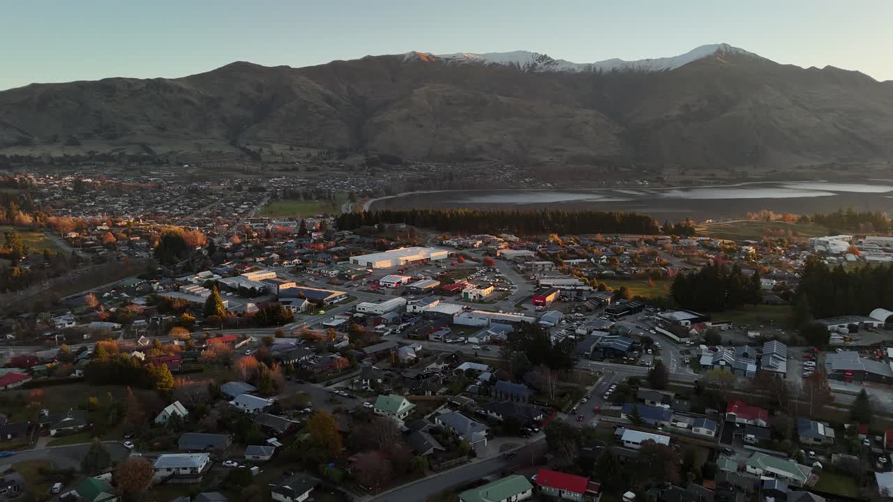 Wanaka town in winter season. With lake and houses. Aerial wide shot. Morning sunrise in city of New Zealand. Snowy summits of mountains