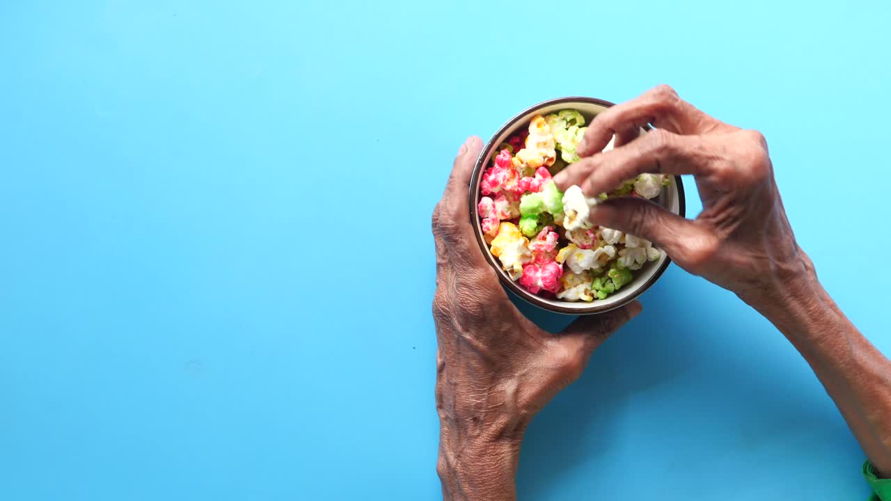 persona de edad avanzada comiendo palomitas de maíz