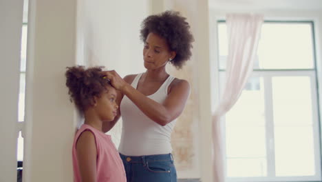 smiling black woman measuring her daughter's height at the wall