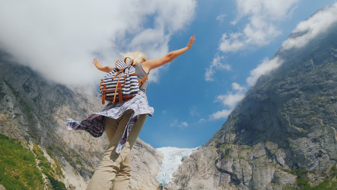 una mujer sana levantó las manos con alegría de pie en el fondo del glaciar brixdal en noruega