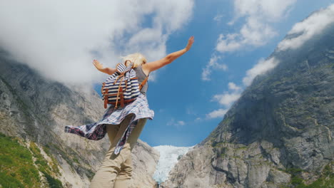 a healthy woman raised her hands joyfully standing on the background of the brixdal glacier in norwa